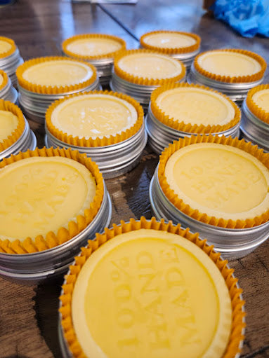 Stacks of tan lotion bars with decorative cases on a metal tray.