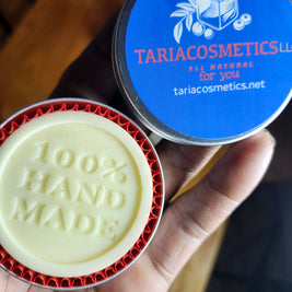 Round lotion bar with '100% handmade' branding held by a hand, next to a blue container labeled 'Taria Cosmetics'