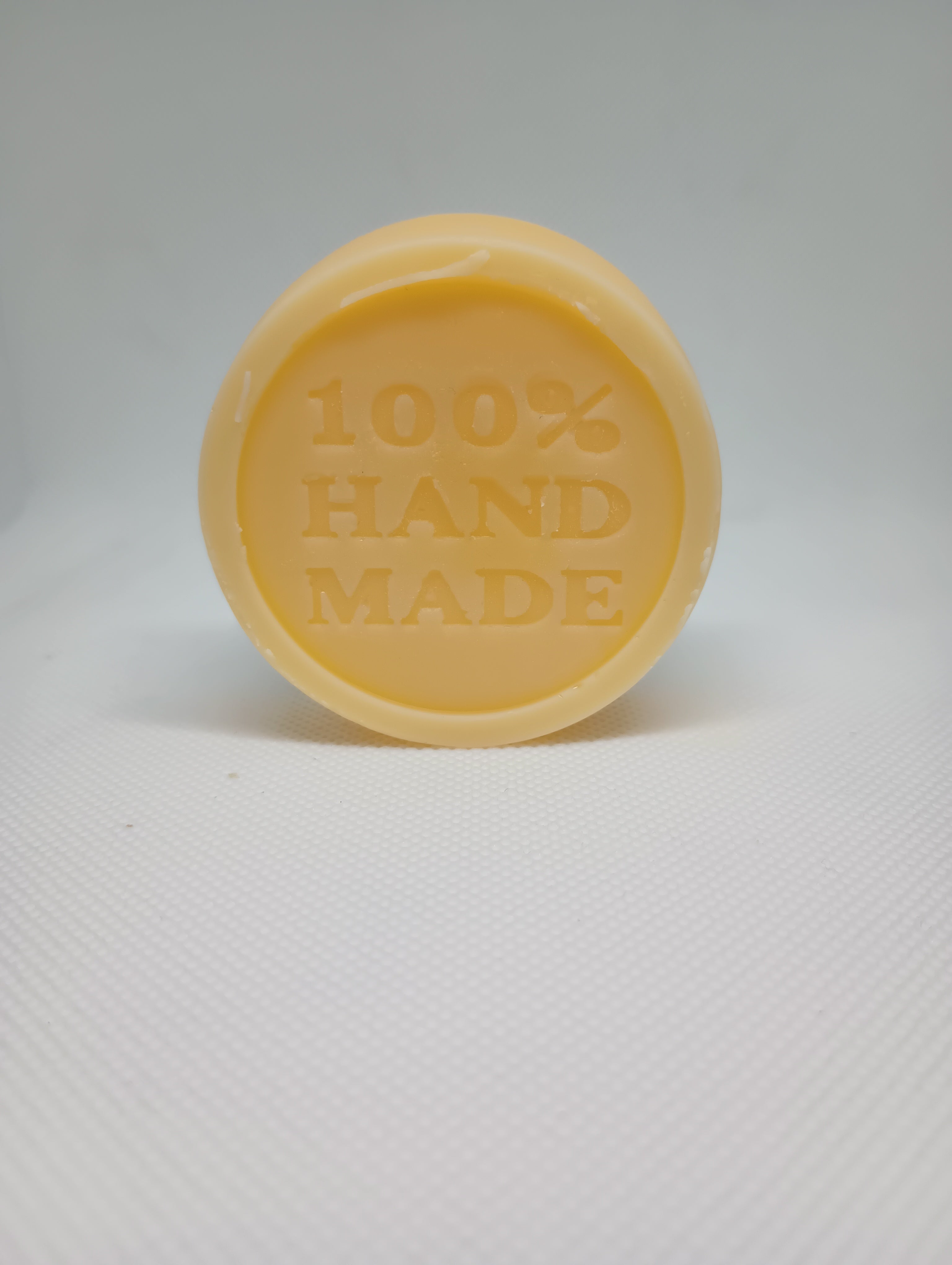 A tan, circular lotion bar is stamped with the words 