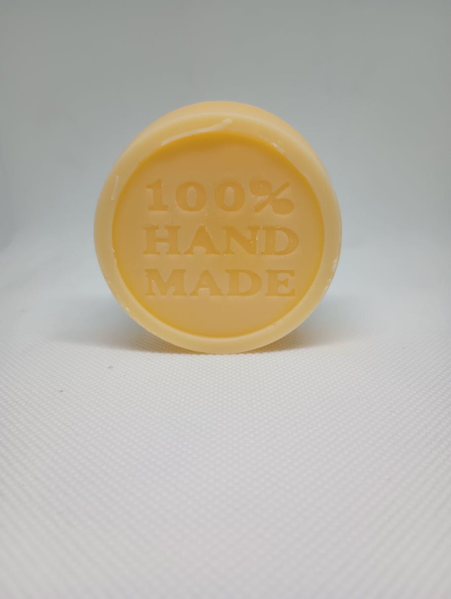 A tan, circular lotion bar is stamped with the words 