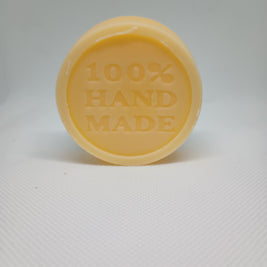 A tan, circular lotion bar is stamped with the words 