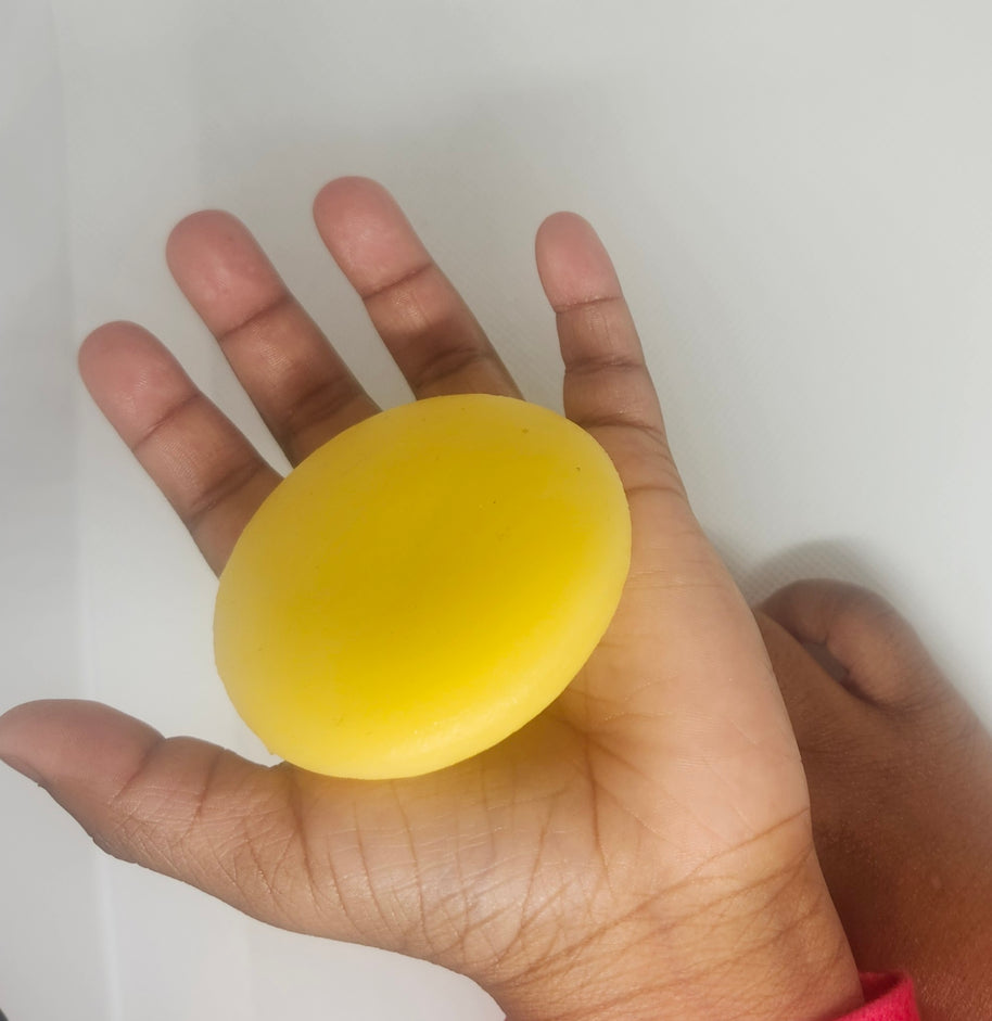 Child's hand open with tan lotion bar in it.