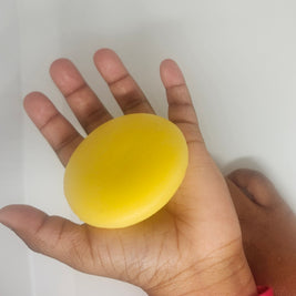 Child's hand open with tan lotion bar in it.