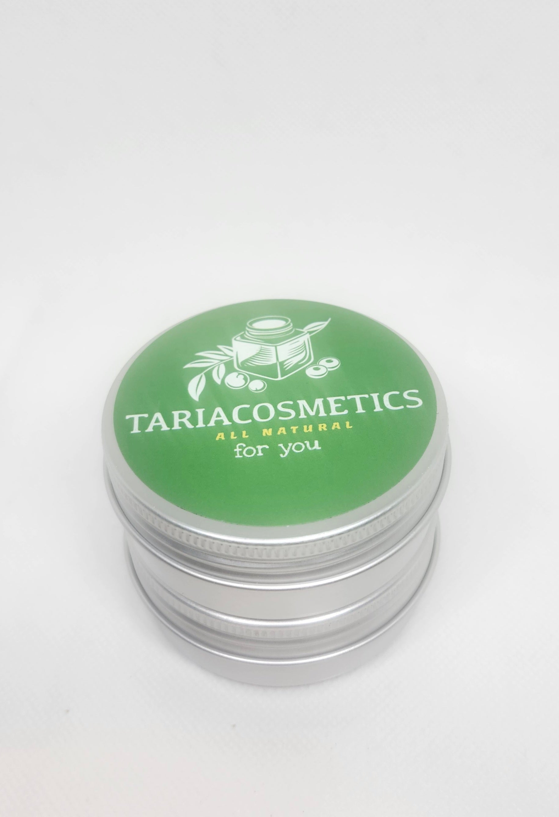 A metal cosmetic tin with a green circular label on the lid featuring the brand name TariaCosmetics  an ALL NATURAL FOR YOU tagline and an illustration of a jar and leaves