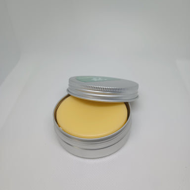 A solid lotion bar inside an open metal tin with a light yellow color, suggesting a creamy texture.