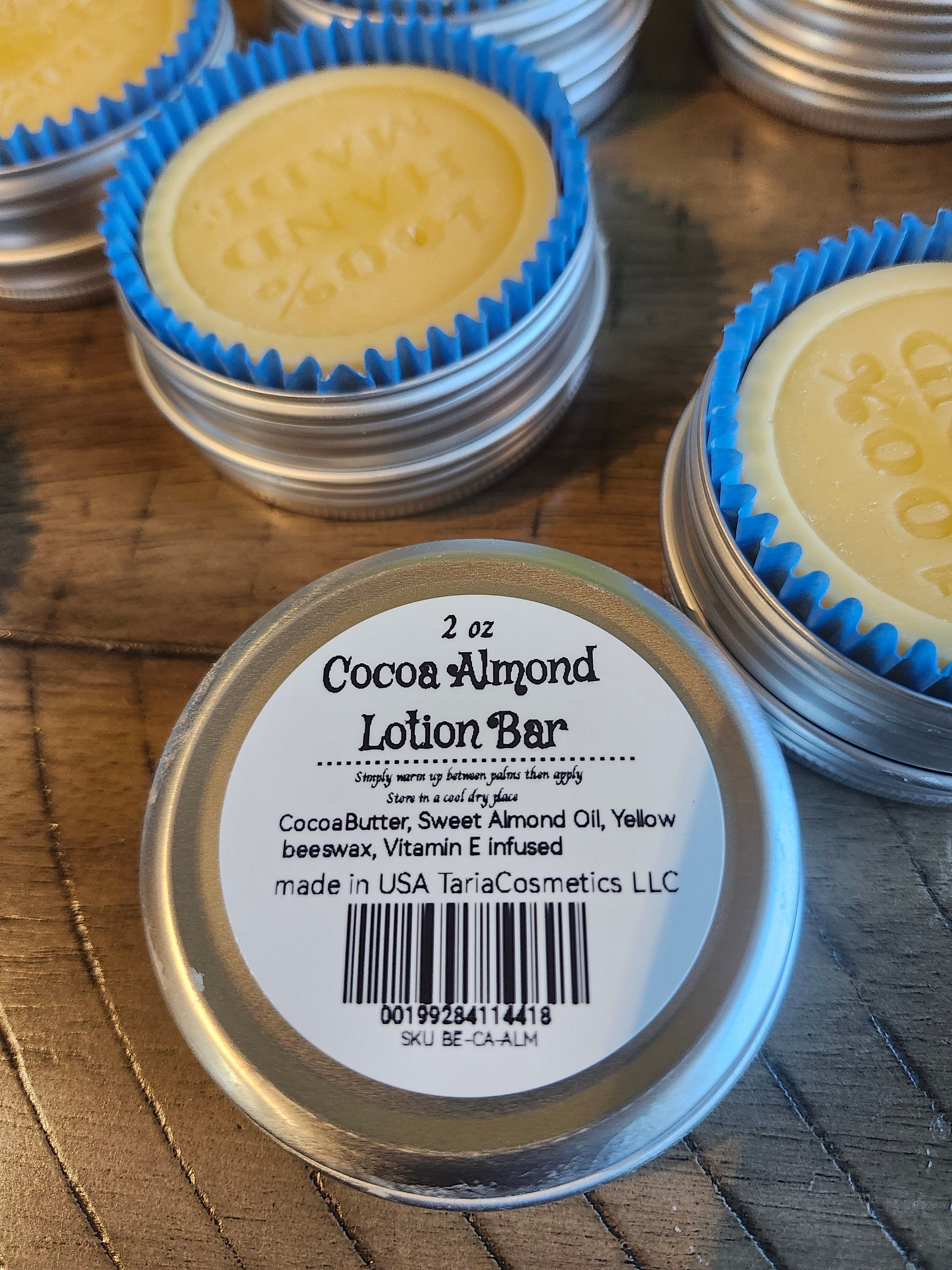 Cocoa Almond Lotion Bar in a metal container with a label on a wooden surface